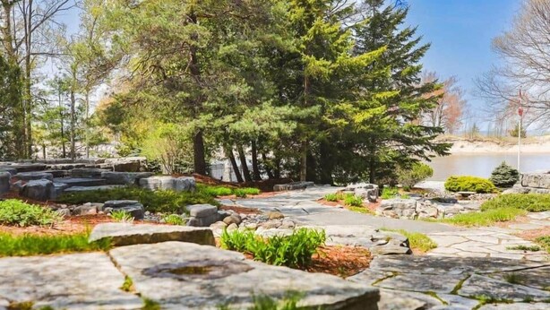 Un sendero de piedra que atraviesa un área ajardinada con árboles y rocas.