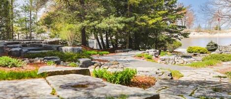 A stone pathway leading through a landscaped area with trees and rocks.