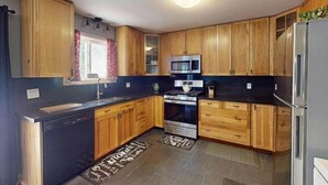 Una cucina con mobili in legno, un forno a microonde in acciaio inossidabile e una lavastoviglie.