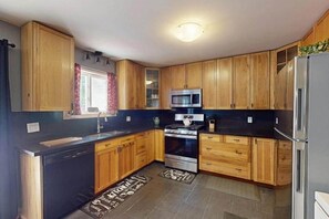 A kitchen with wooden cabinets, a stainless steel microwave, and a dishwasher. - Wavy Daze in Wasaga Beach (Wasaga Beach)