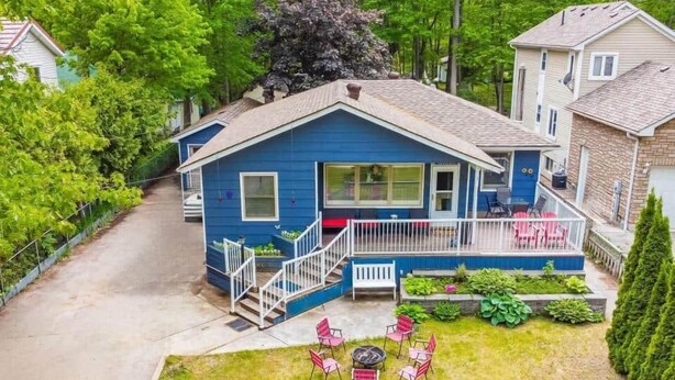 Una casa blu con un portico, un piccolo patio e un giardino con sedie.