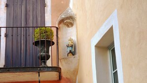 A building corner with a balcony, a window, and a small statue. - Atypical and central apartment in Fontaine de Vaucluse (Fontaine-de-Vaucluse)
