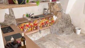 A kitchen with a stone wall, a sink, a countertop, and a bottle of wine. - Atypical and central apartment in Fontaine de Vaucluse (Fontaine-de-Vaucluse)