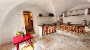 A kitchen with a stone countertop, a red table, and a chair. - Atypical and central apartment in Fontaine de Vaucluse (Fontaine-de-Vaucluse)