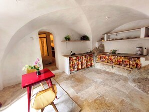 Una cocina con encimera de piedra, una mesa roja y una silla.