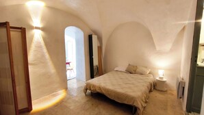 A bedroom with a bed, a bedside table, and a lamp. There is an arched doorway leading to another room. - Atypical and central apartment in Fontaine de Vaucluse (Fontaine-de-Vaucluse)