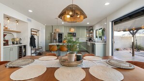 A modern kitchen with a central island, pendant lighting, and a dining area with woven placemats.