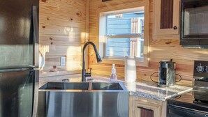 Una cucina compatta con un lavello in acciaio inossidabile, mobili in legno, una finestra e un forno integrato.