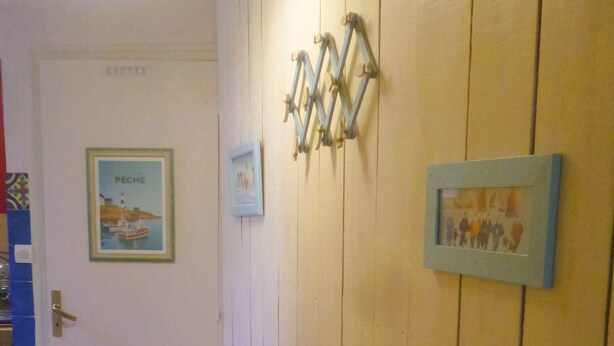 Een gang met houten lambrisering, een radiator en ingelijste foto’s aan de muur.