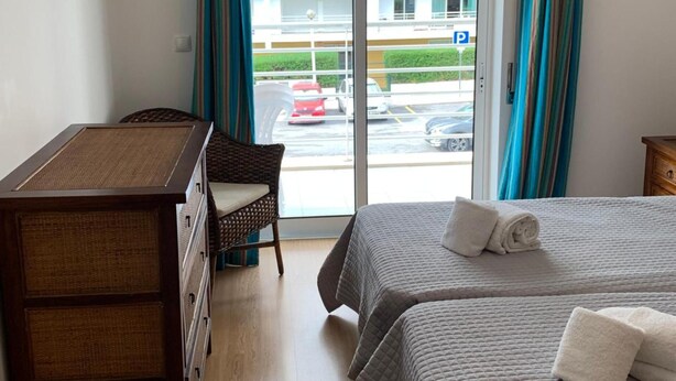 Ein Hotelzimmer mit Bett, Schreibtisch, Stuhl und Blick auf die Straße durch eine Glastür.