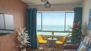 A living room with a TV, wooden panel wall, a view of the sea, a round table with chairs, and a sofa. - Perfect 3-bedroom apartment in enchanting Callao for your stay (Callao)