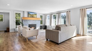 Een moderne woonkamer met een open haard, een bank en een groot raam met gordijnen.