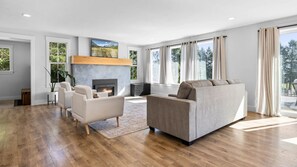 A modern living room with a fireplace, a sofa, and a large window with curtains. - Spacious family-friendly 5-bedroom house in Kalispell, MT (Kalispell)