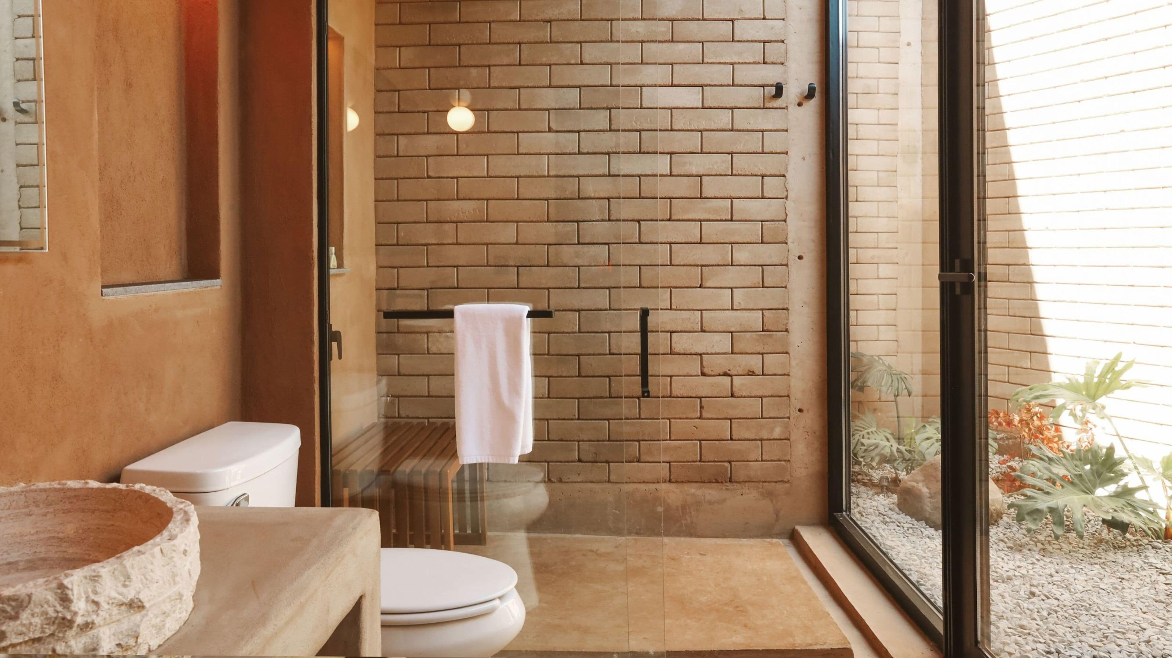 A bathroom with a toilet, a sink, and a shower area with a towel hanging on a rack.