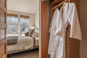 Ein Schlafzimmer mit Bett, Fenster und Kleiderschrank mit Bademänteln.