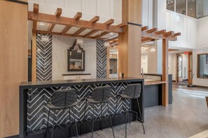 Eine moderne Bar mit einem schwarz-weißen Zickzackmuster, Holzbalken und einem großen Spiegel.