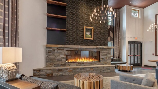 A modern lobby with a stone fireplace, seating areas, and a large window. - VIP Palisades Condo A+ Location Views Hot-Tub (Olympic Valley)