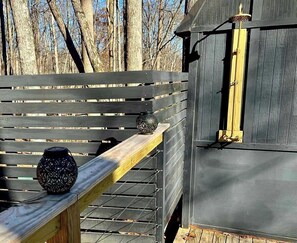 Eine Holzterrasse mit Metallgeländer, einer Bank und zwei dekorativen Laternen.