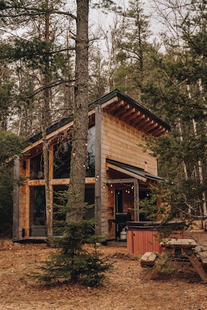 A rustic cabin with a wooden exterior, large windows, and a porch area.