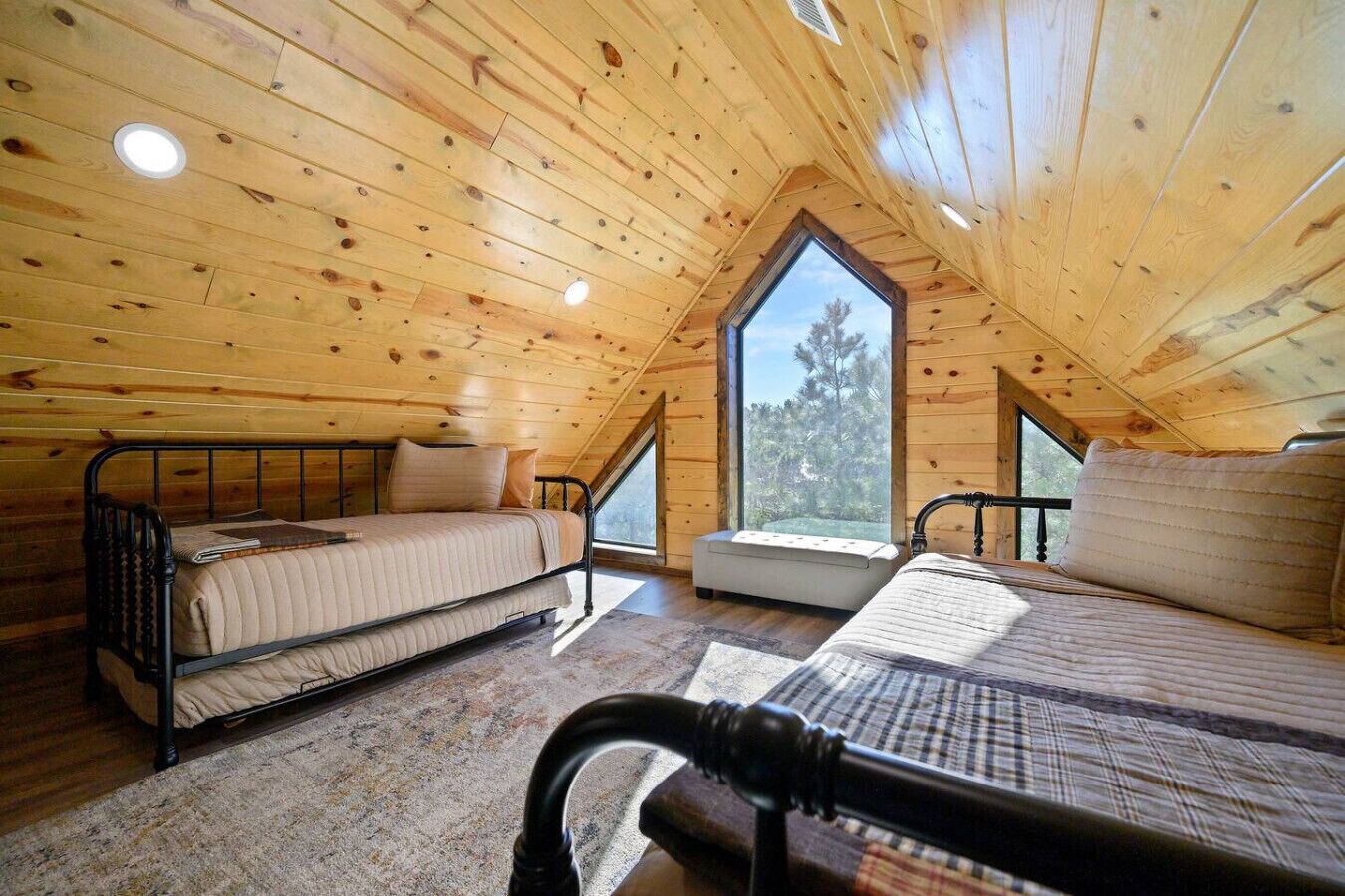 Ein gemütliches Schlafzimmer im Dachgeschoss mit schrägen Wänden, zwei Betten, einem Fenster und einem Oberlicht.