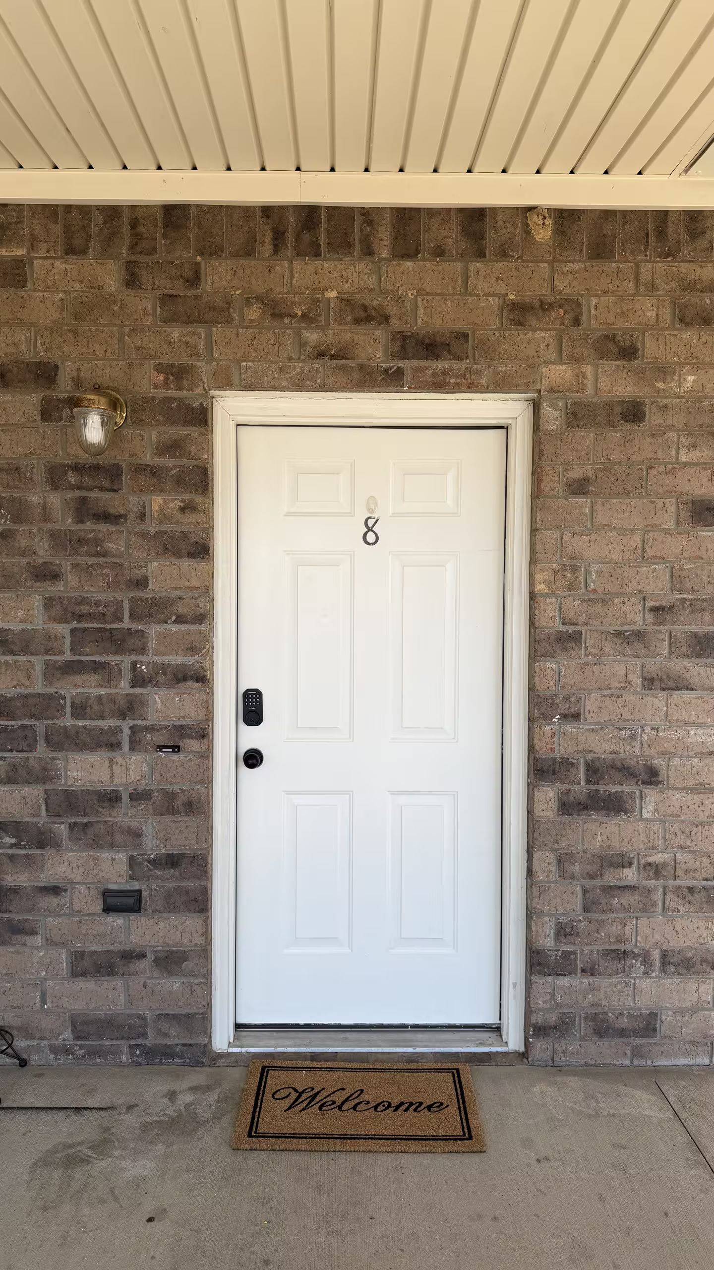 A white door with a keypad lock and a small mailbox to the left.