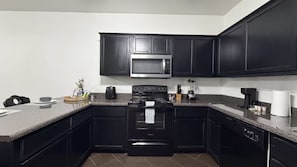 Una cocina con armarios negros, un microondas, una estufa y un lavavajillas.
