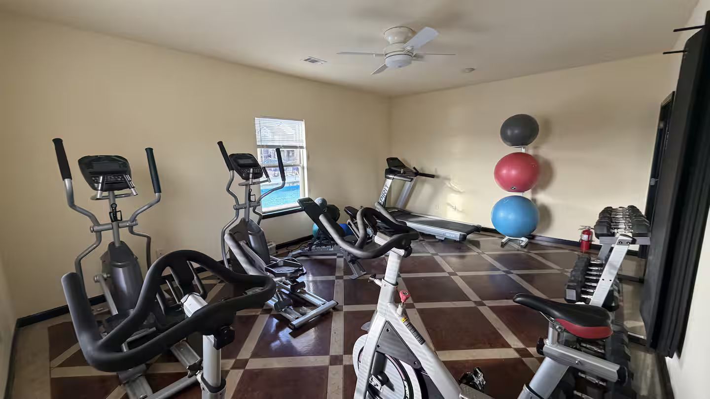 Une salle de sport équipée de machines de cardio, d’un tapis de course et de ballons d’exercice.