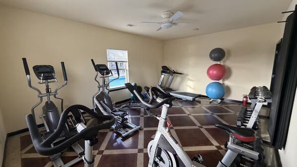 A gym with cardio machines, a treadmill, and exercise balls.