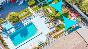 Vue aérienne d’un hôtel avec une piscine, des chaises longues et un espace de jeux pour enfants.