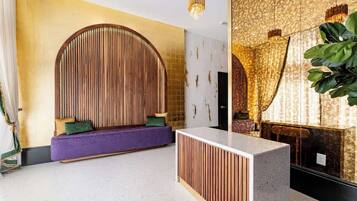 A reception area with a curved wooden wall, a purple sofa, and a reception desk.