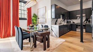 A modern kitchen with dark cabinets, stainless steel appliances, and a marble backsplash. - Luxury Poolside Suite | 4 King Beds+Sleeper Sofa (New Orleans)