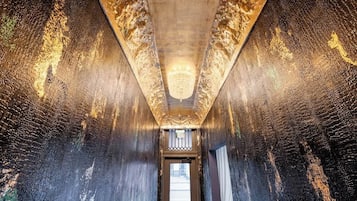 A corridor with ornate wall patterns and a chandelier.