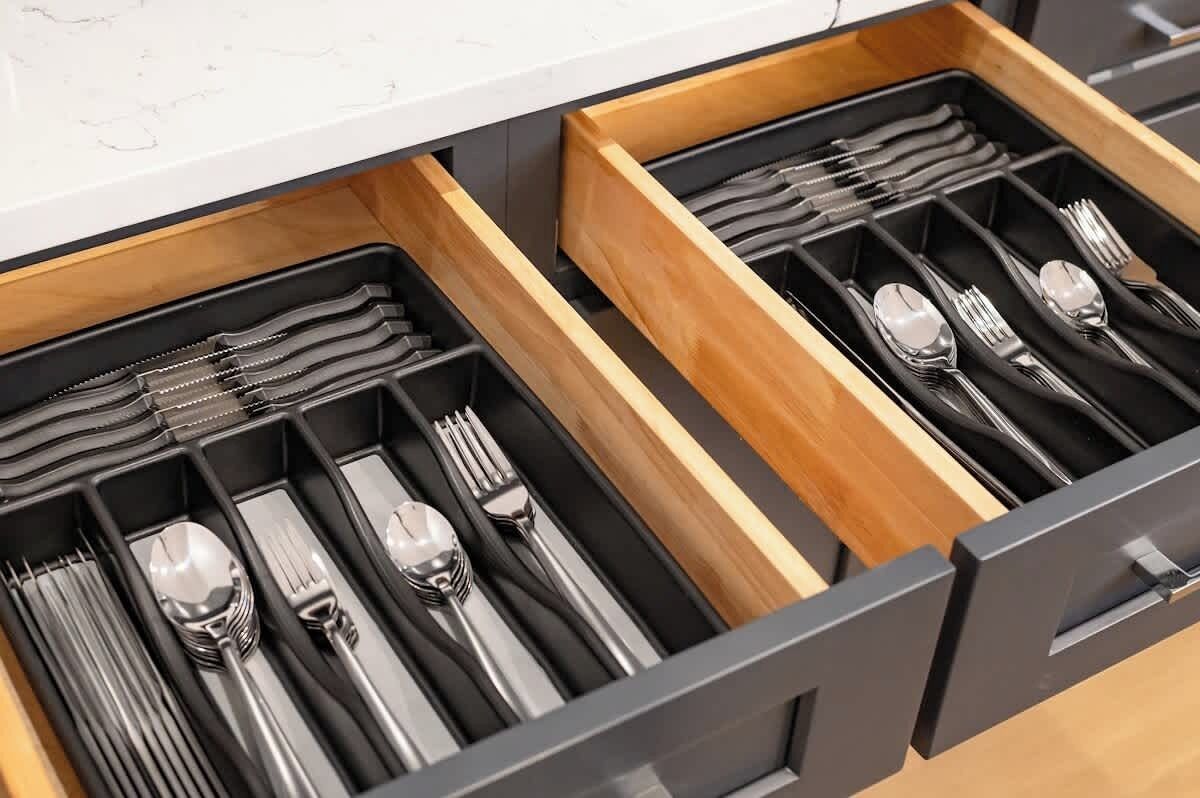 A drawer with neatly organized cutlery including forks, spoons, and knives.