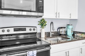 Una cucina con piano cottura in acciaio inossidabile, forno a microonde, lavandino e macchina per il caffè.