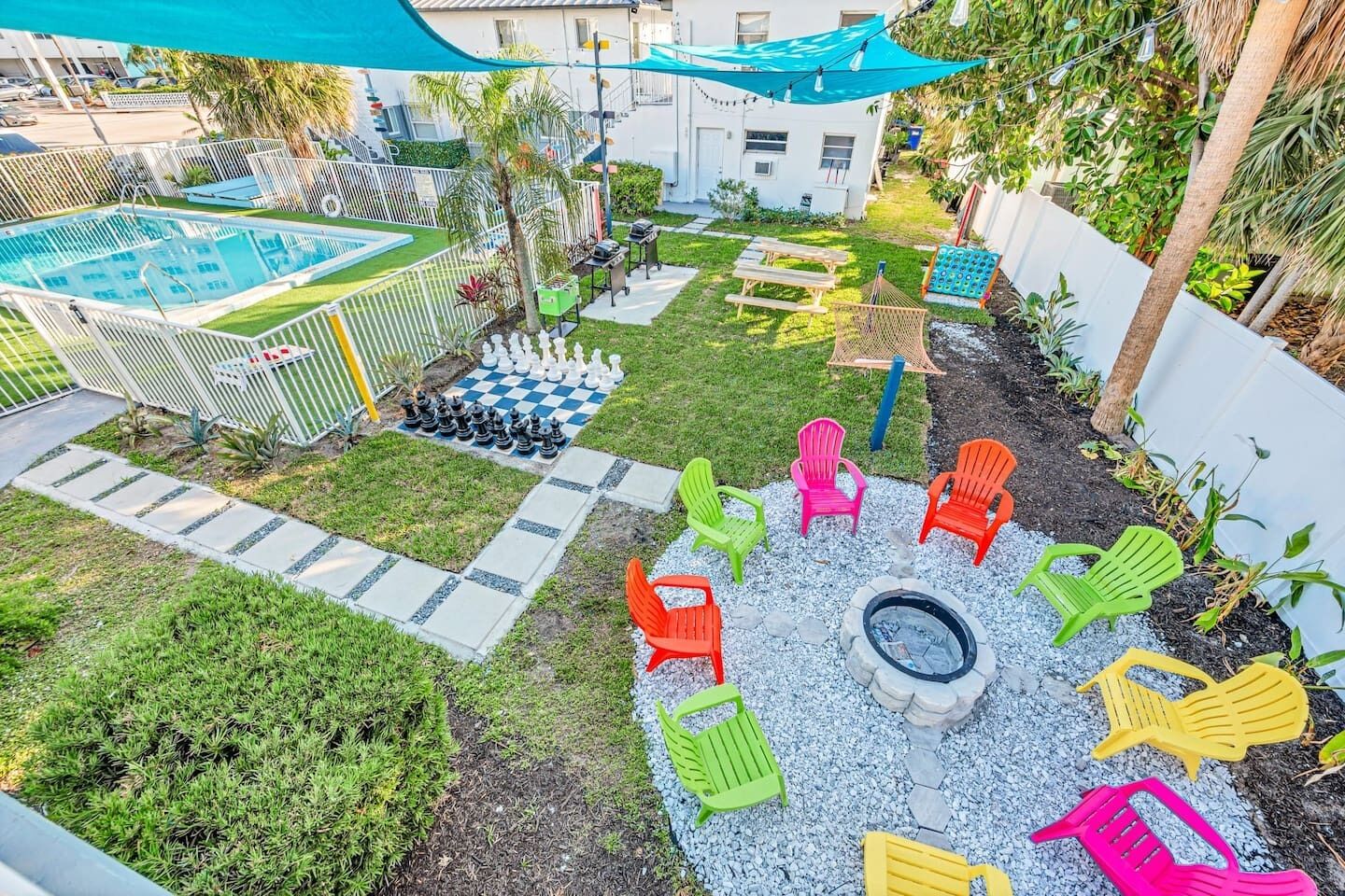 A backyard with a pool, outdoor seating, and a fire pit.