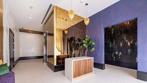 A modern lobby with a reception desk, a seating area, and a large abstract painting on the wall. - On Streetcar Line | 5 King Beds | Blackout Drapes (New Orleans)