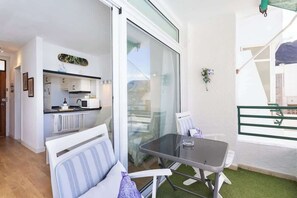 Eine moderne Wohnung mit Küche, einem Balkon mit Glasdoor und einem Essbereich mit Tisch und Stühlen.