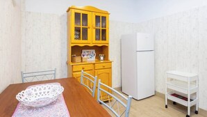 A dining area with a wooden table, chairs, a white basket, a yellow cabinet, and a white refrigerator. - Apartamento Vistas Al Mar y Al Teide (Tacoronte)