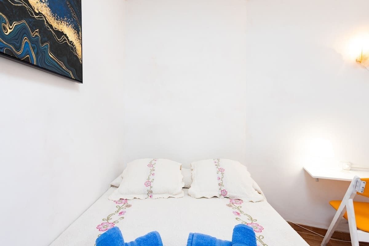 Ein Schlafzimmer mit Bett, Kissen, Schreibtisch und Stuhl.