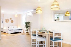 A bright room with a bed, a dining table with chairs, and a large mirror. - Bajamar Waterfront Apt (Bajamar)