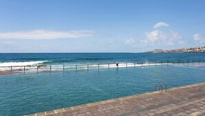 En swimmingpool med utsikt över havet och en avlägsen stadsbild.