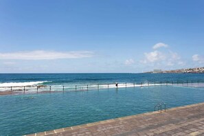 Ein Pool mit Blick auf den Ozean und eine entfernte Skyline.