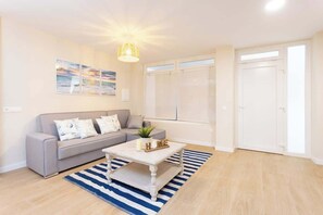 Ein Wohnzimmer mit einer Couch, einem Couchtisch, einem Teppich und einer Deckenleuchte.