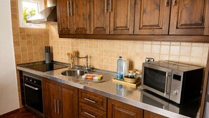 Een keuken met houten kastjes, een RVS spoelbak, een magnetron en een inbouwoven.