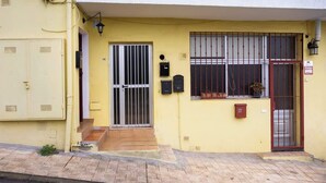 A yellow building with a gated entrance, a mailbox, and a small window with a potted plant. - Apartamento Campo Rosa Tacoronte (Tacoronte)