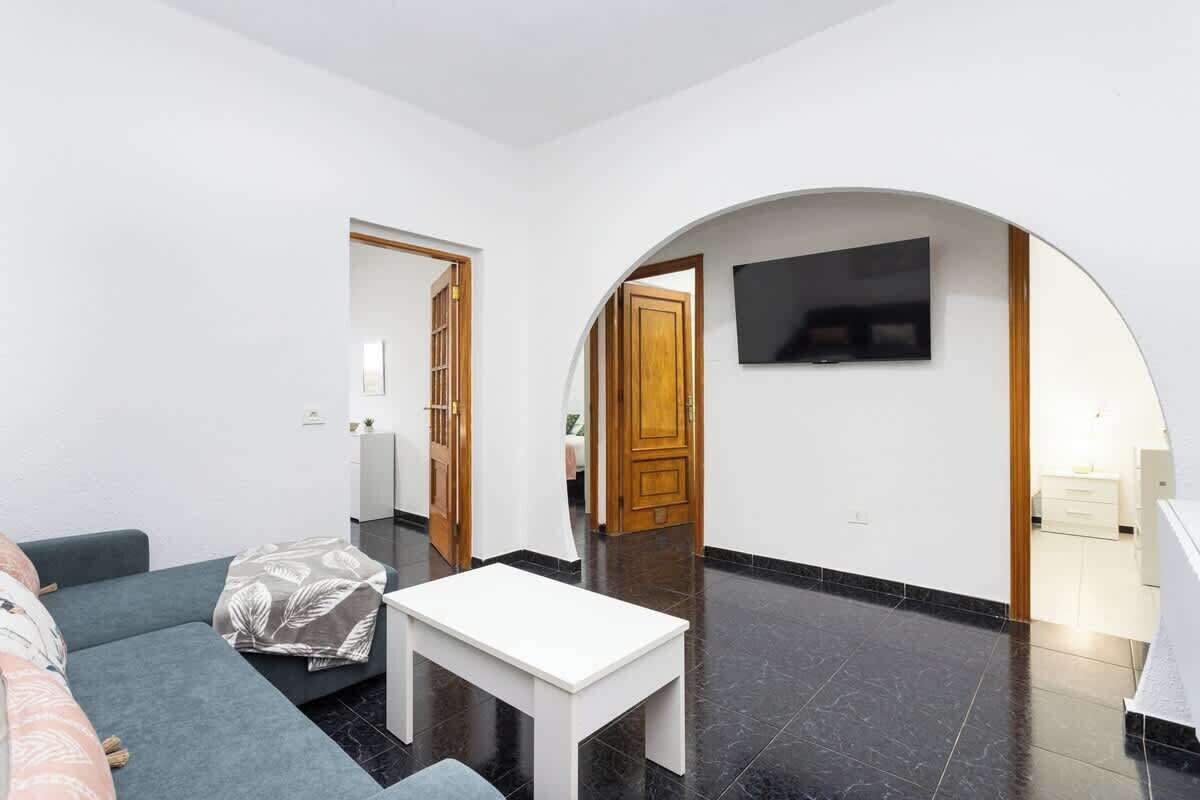 A modern living room with a sofa, a white table, and a TV mounted on an arched wall.