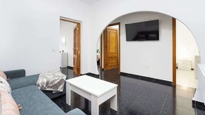 A modern living room with a sofa, a white table, and a TV mounted on an arched wall. - Apartamento Campo Rosa Tacoronte (Tacoronte)
