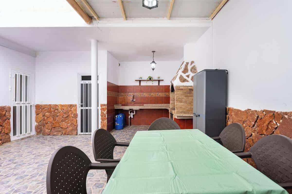 An outdoor patio with a table and chairs, a brick oven, and a water dispenser.
