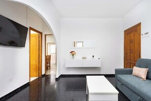 A modern living room with a flat-screen TV, a white console table with decorative items, a grey sofa, and a white coffee table. - Terrace & BBQ Apt in Central Tacoronte, Tenerife (Tacoronte)