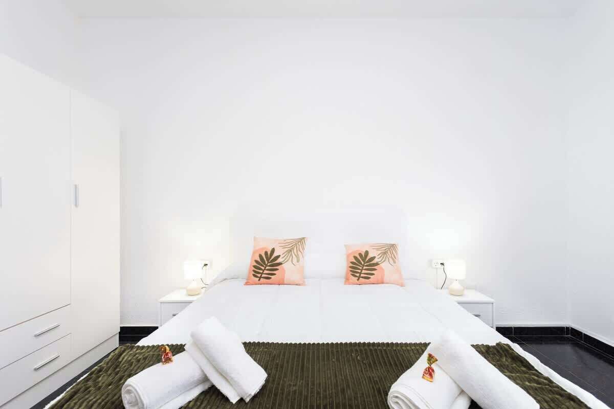 Een hotelkamer met een bed, twee nachtkastjes, een lamp en een groen kleed.